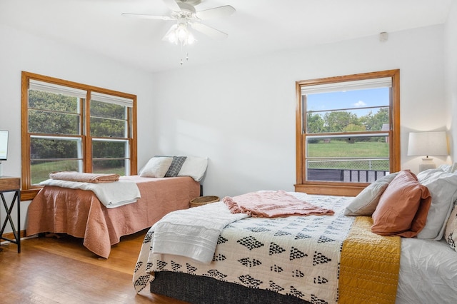 bedroom featuring ceiling fan, wood-type flooring, and multiple windows