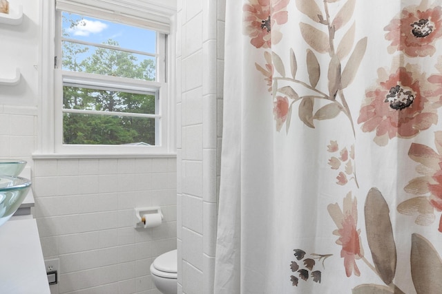 bathroom featuring toilet and tile walls