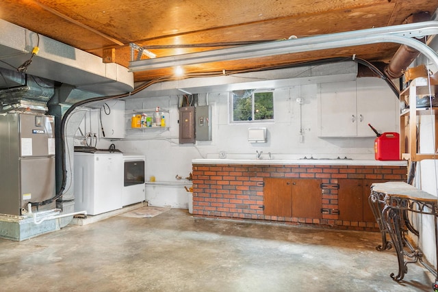 basement with sink, a workshop area, independent washer and dryer, electric panel, and heating unit