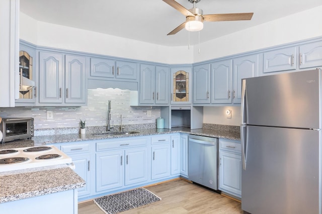 kitchen featuring sink, light wood-type flooring, blue cabinetry, tasteful backsplash, and stainless steel appliances