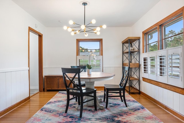 dining area featuring light hardwood / wood-style flooring, a healthy amount of sunlight, and an inviting chandelier