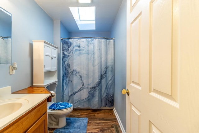 bathroom with a skylight, walk in shower, vanity, wood-type flooring, and toilet