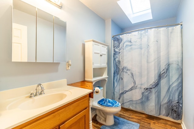 bathroom with a skylight, toilet, vanity, and hardwood / wood-style flooring