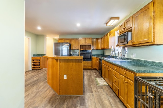 kitchen featuring a breakfast bar, sink, black appliances, hardwood / wood-style flooring, and a kitchen island