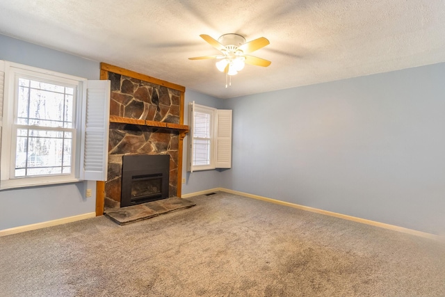 unfurnished living room with carpet, ceiling fan, a fireplace, and a textured ceiling