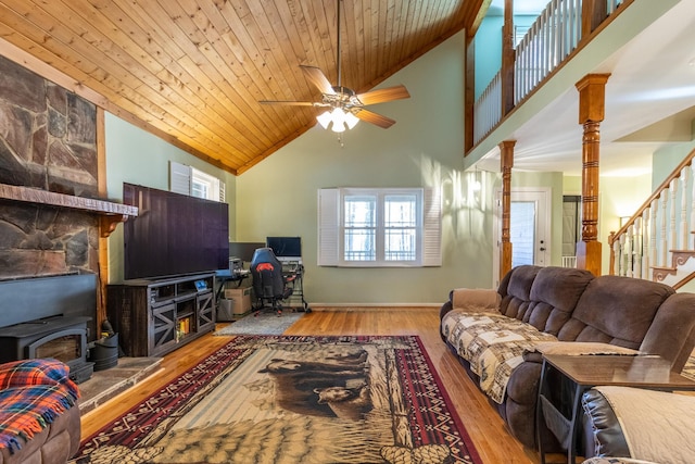 living room with a wood stove, ceiling fan, a healthy amount of sunlight, and hardwood / wood-style flooring