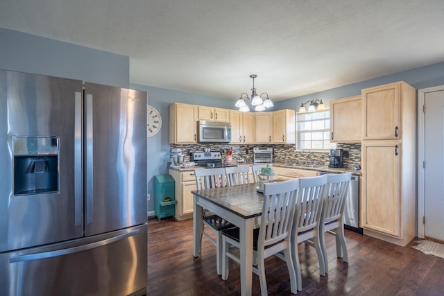 kitchen with decorative light fixtures, light brown cabinets, stainless steel appliances, and dark wood-type flooring