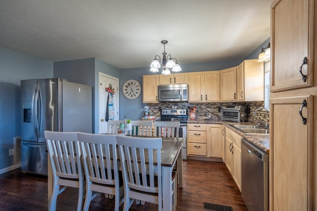 kitchen with light brown cabinetry, stainless steel appliances, and dark hardwood / wood-style floors