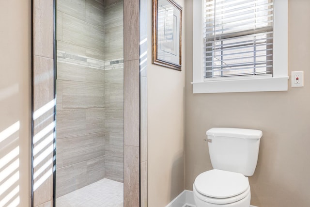 bathroom featuring toilet and a tile shower