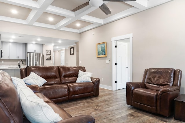 living room featuring beam ceiling, light hardwood / wood-style flooring, ceiling fan, and coffered ceiling