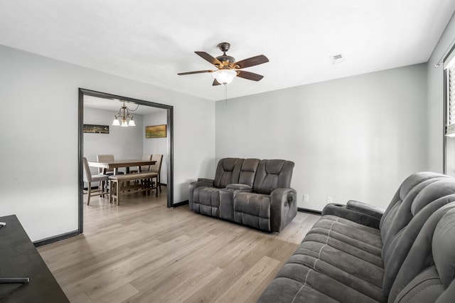 living room featuring light hardwood / wood-style floors and ceiling fan with notable chandelier