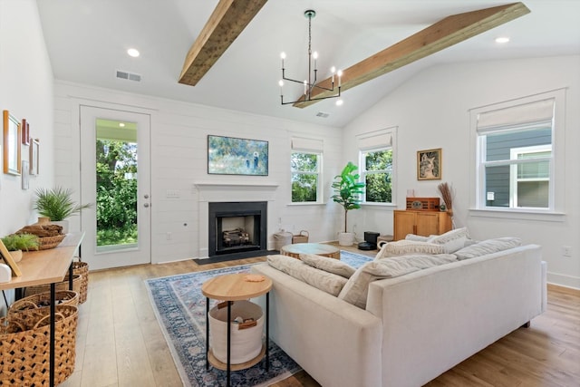 living room with lofted ceiling with beams, a notable chandelier, and light wood-type flooring