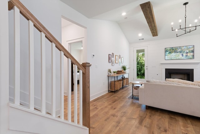 living room with an inviting chandelier, lofted ceiling with beams, and light wood-type flooring