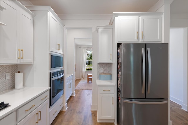 kitchen with stainless steel appliances, white cabinetry, and tasteful backsplash