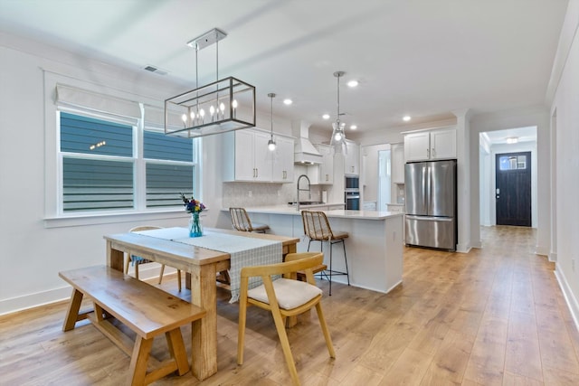 dining room featuring light hardwood / wood-style floors, ornamental molding, and sink