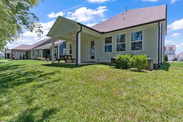 rear view of property featuring a lawn and central air condition unit