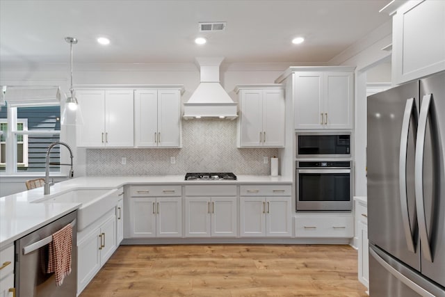 kitchen featuring premium range hood, sink, white cabinets, and stainless steel appliances