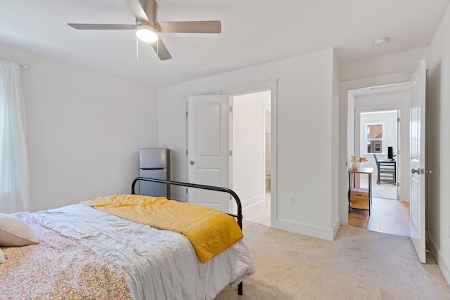 carpeted bedroom with ceiling fan and stainless steel fridge