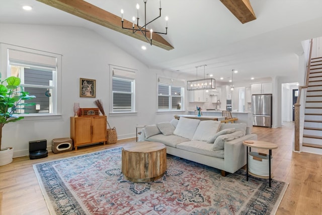 living room with plenty of natural light, lofted ceiling with beams, and light hardwood / wood-style flooring