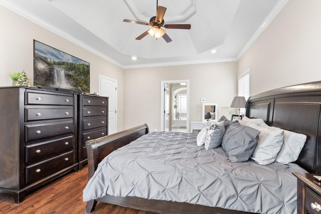 bedroom featuring ceiling fan, connected bathroom, dark wood-type flooring, ornamental molding, and a tray ceiling