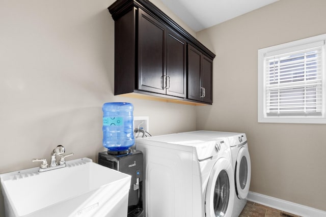 clothes washing area with cabinet space, baseboards, separate washer and dryer, and a sink