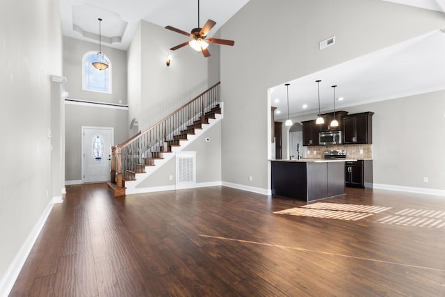 kitchen with dark wood-type flooring, baseboards, open floor plan, light countertops, and appliances with stainless steel finishes