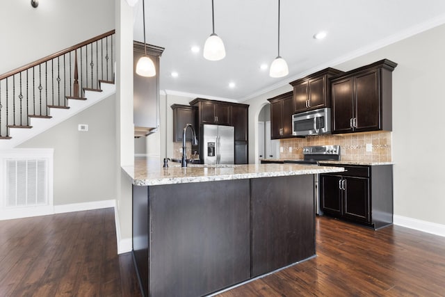 kitchen with dark brown cabinetry, stainless steel appliances, a sink, visible vents, and decorative backsplash