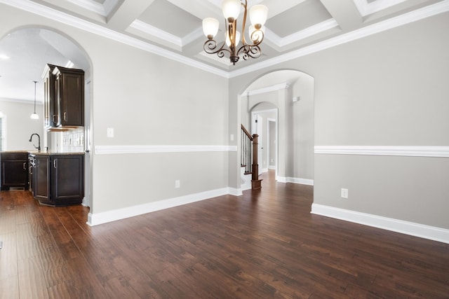 spare room with baseboards, arched walkways, coffered ceiling, and dark wood-type flooring