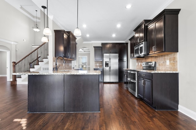 kitchen with a peninsula, appliances with stainless steel finishes, and light stone counters