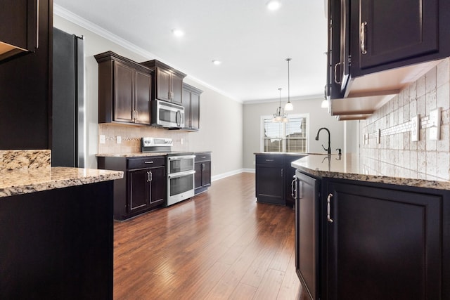 kitchen featuring light stone countertops, appliances with stainless steel finishes, dark wood-type flooring, and ornamental molding