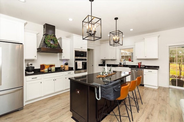 kitchen featuring appliances with stainless steel finishes, light hardwood / wood-style floors, pendant lighting, a kitchen island, and custom exhaust hood