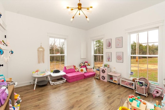 game room featuring hardwood / wood-style floors, a healthy amount of sunlight, and a chandelier