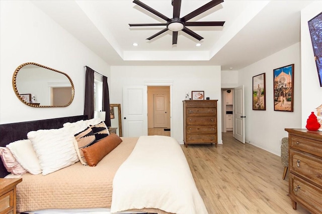 bedroom with a tray ceiling, ceiling fan, and light hardwood / wood-style floors