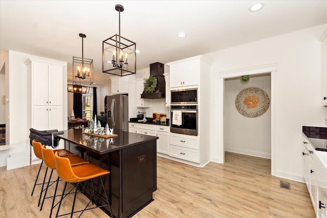 kitchen with a breakfast bar, appliances with stainless steel finishes, a center island, and light hardwood / wood-style flooring