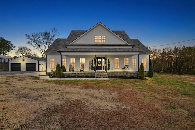 back house at dusk with a lawn, a porch, a garage, and an outbuilding