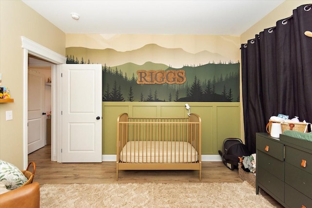 bedroom featuring light hardwood / wood-style floors and a crib