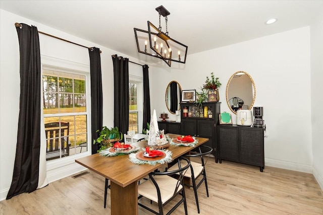 dining space featuring light hardwood / wood-style flooring and a chandelier