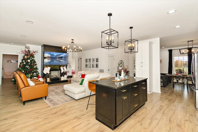 kitchen with a breakfast bar, a kitchen island, light hardwood / wood-style floors, and hanging light fixtures