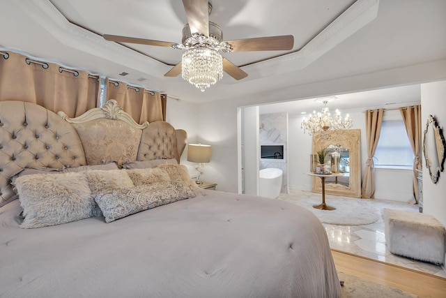 bedroom with ceiling fan with notable chandelier, a raised ceiling, light wood-type flooring, and ensuite bathroom