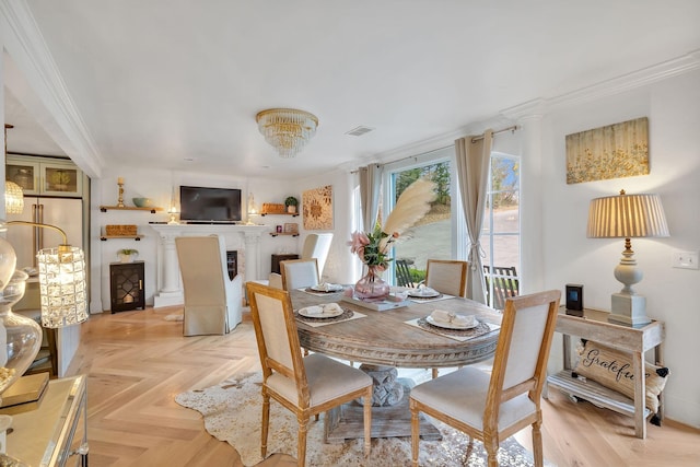 dining room with an inviting chandelier, light parquet flooring, and ornamental molding