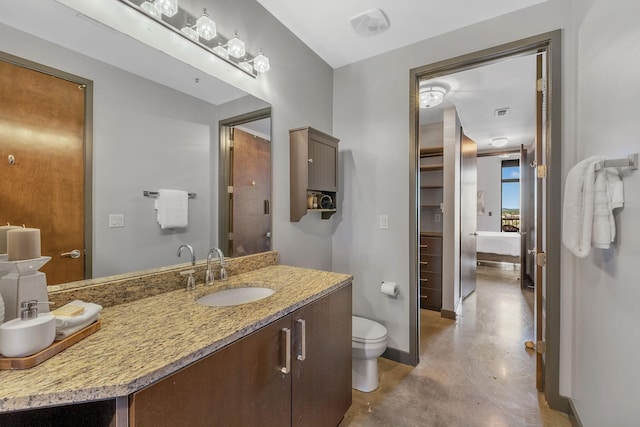 bathroom with vanity, toilet, and concrete floors