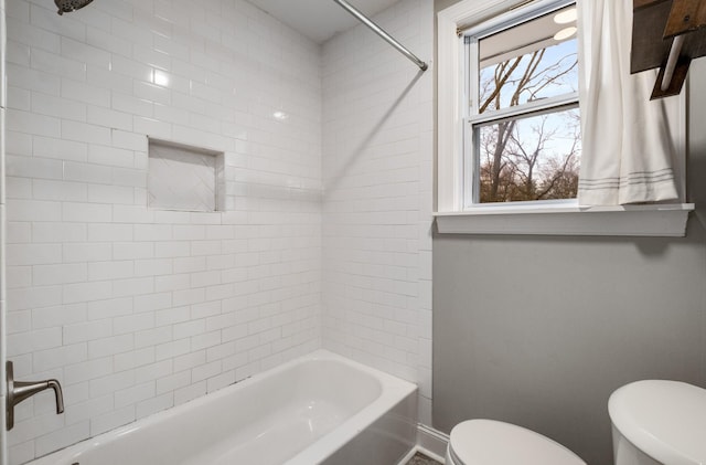 bathroom with toilet and tiled shower / bath