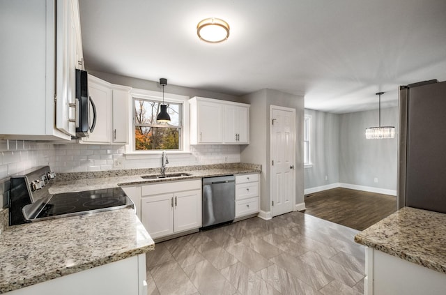 kitchen with appliances with stainless steel finishes, light stone counters, sink, decorative light fixtures, and white cabinetry