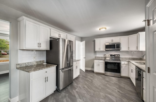 kitchen with stone counters, sink, decorative backsplash, white cabinetry, and stainless steel appliances