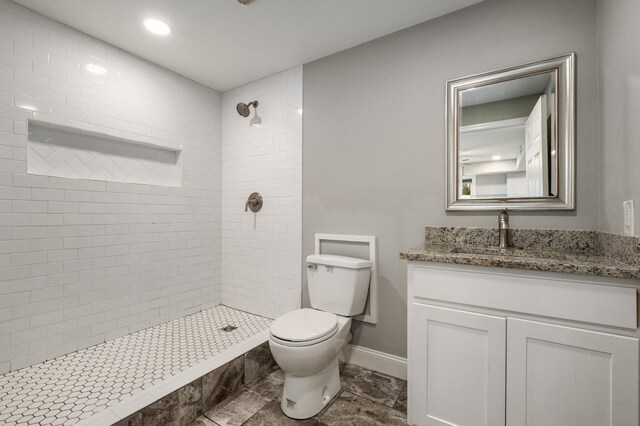 bathroom featuring tiled shower, vanity, and toilet