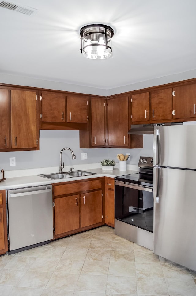 kitchen with sink, light tile patterned flooring, stainless steel appliances, and extractor fan