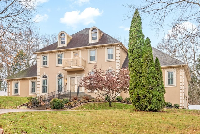 colonial inspired home with a balcony and a front lawn