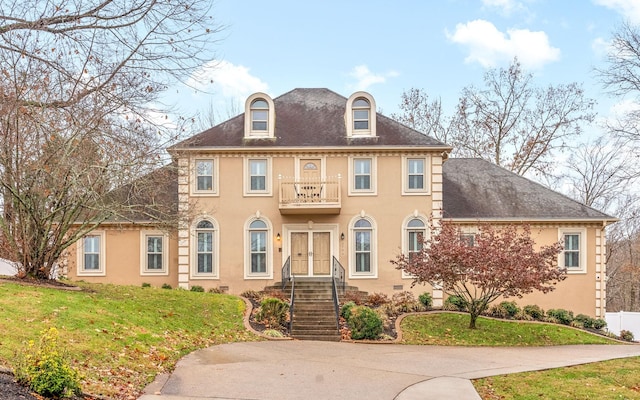 colonial house featuring a balcony and a front yard