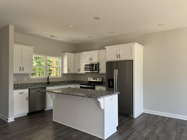 kitchen featuring white cabinets, appliances with stainless steel finishes, a kitchen island, and dark wood-type flooring