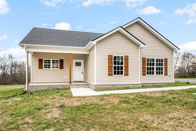 view of front facade featuring roof with shingles, covered porch, and a front lawn